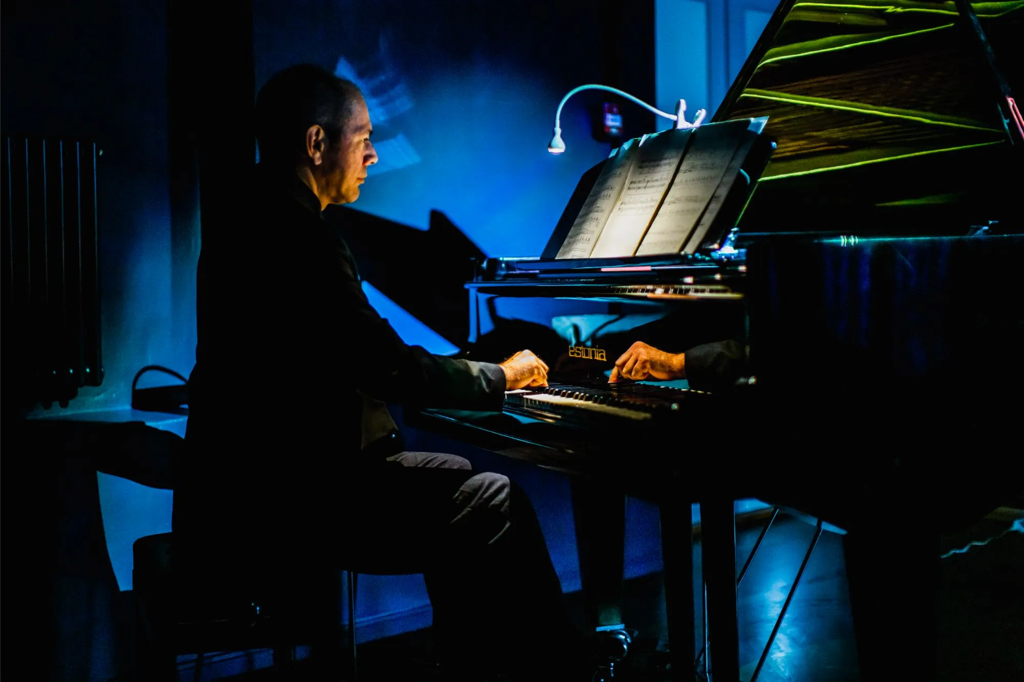 Pianist vaatab noote ja mängib hubase sinise valguse käes Estonia kontsertklaveril
