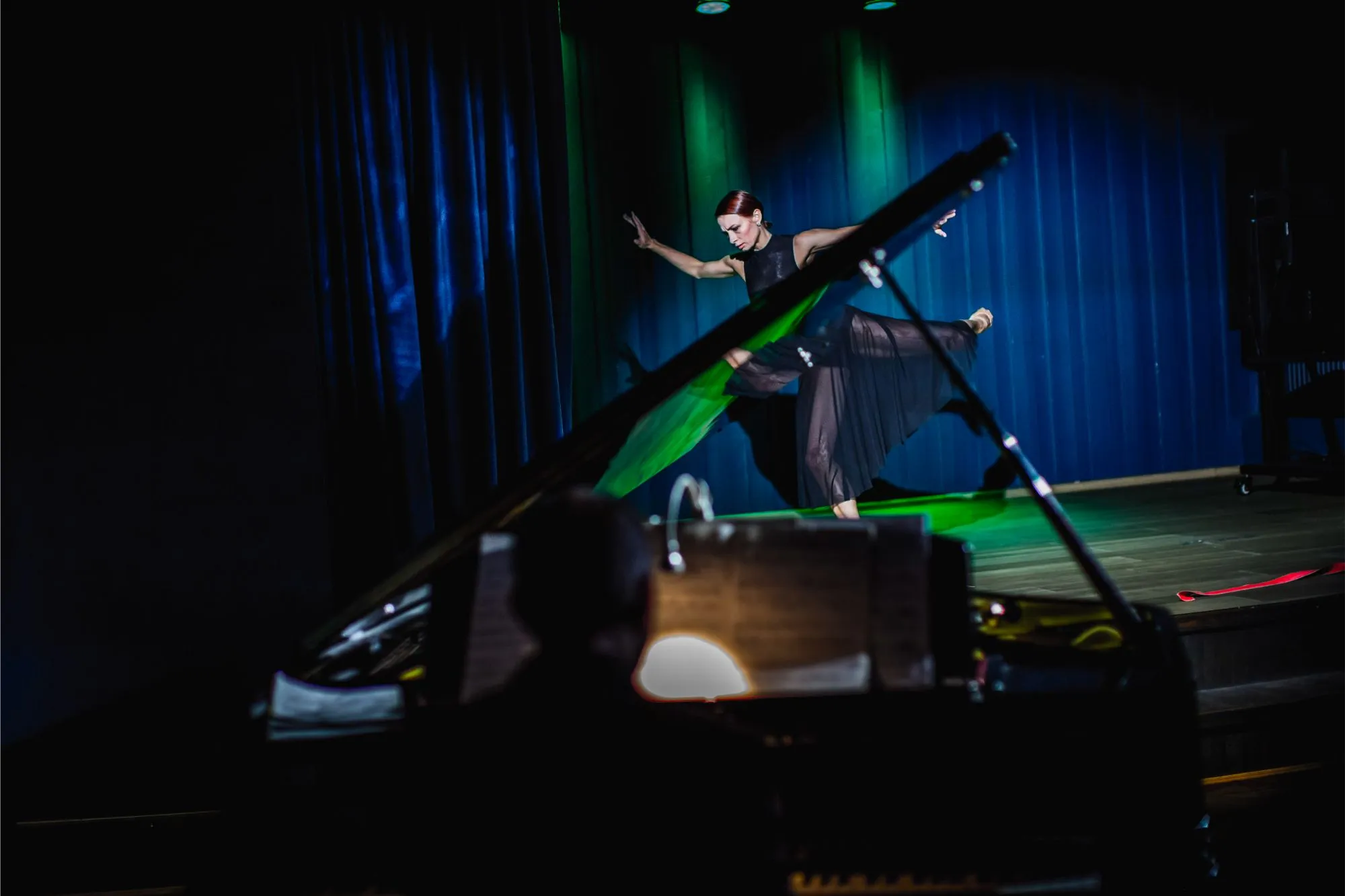 Baleriin laval, pianist suure klaveri taga hämaras kontserdisaalis.
