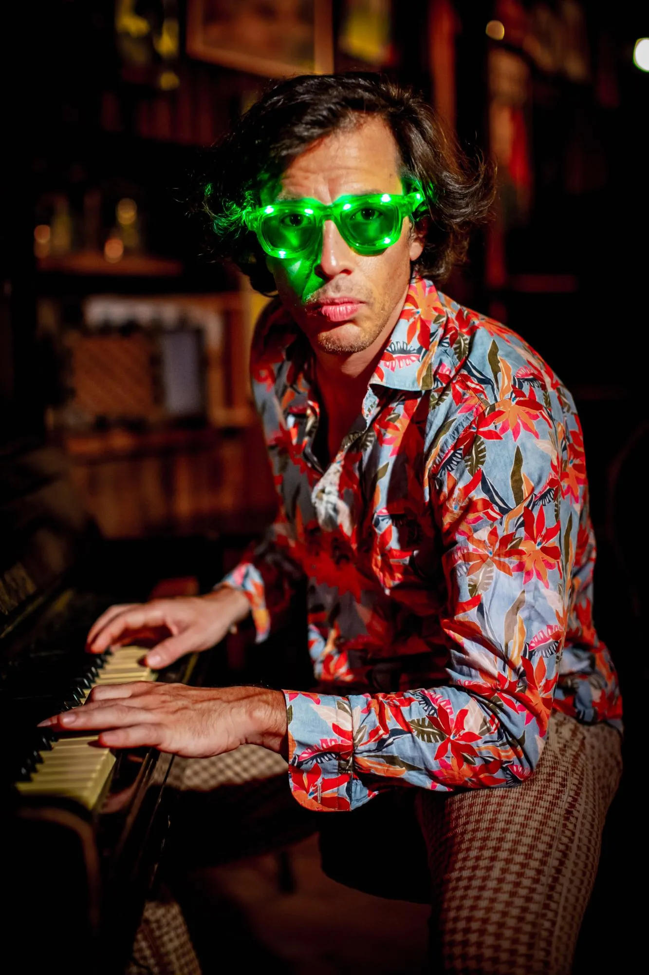 Pianist esineb hubases kohas püstklaveril, rohelised prillid peas.